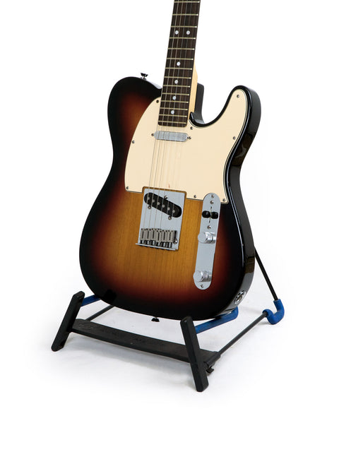 A sunburst electric guitar on a black stand against a white background.