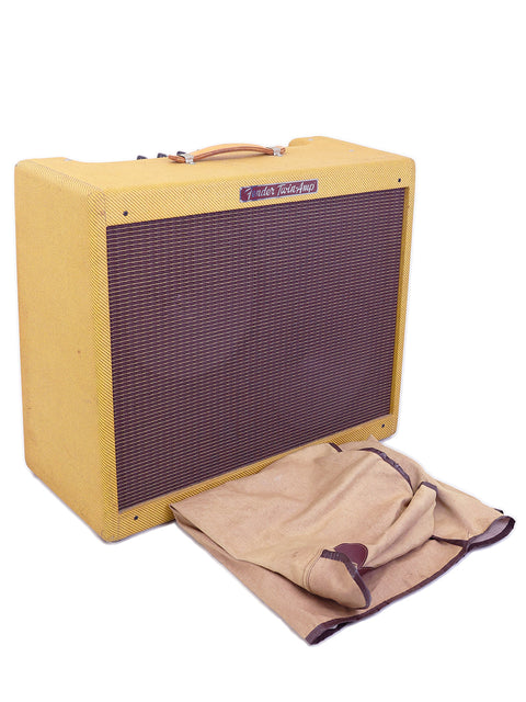A vibrant yellow 1957 Fender Twin Reissue amp from 2006, adorned with a cloth bag, blending retro aesthetics with modern design.