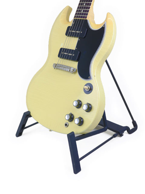 A vibrant yellow Gibson Custom ‘63 SG Special electric guitar resting on a stand, highlighting its unique style.