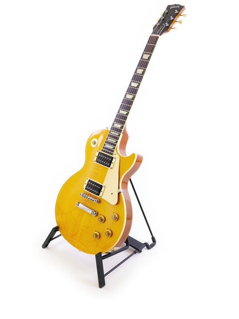 A vibrant yellow Gibson Les Paul Classic 1960 Reissue guitar displayed on a stand with a white backdrop.