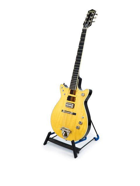 A vibrant yellow Gretsch G6131 Malcolm Young Signature Jet guitar resting on a stand, set against a white background.
