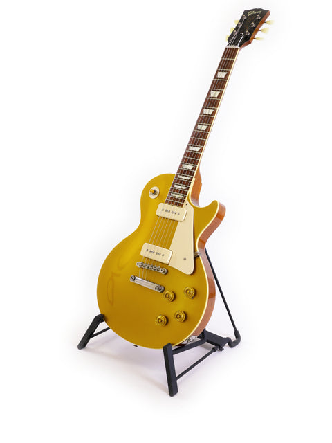 A vibrant yellow guitar, the Gibson Custom Historic VOS LPR-6, displayed on a stand with a simple white backdrop.