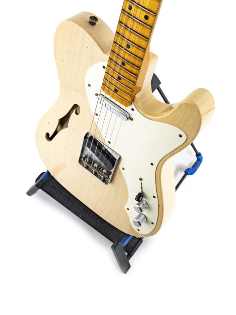 A vintage-style Fender Custom Shop '50s Thinline Relic Telecaster guitar resting on a blue stand, highlighting its craftsmanship.