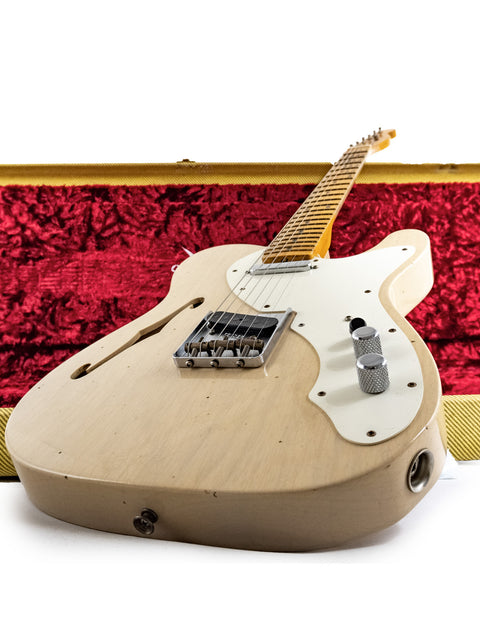 A vintage-style Fender Telecaster guitar resting in a wooden case, elegantly covered with rich red velvet.