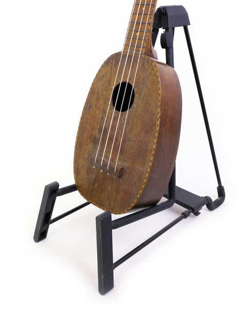 A vintage 1930 Kamaka Pineapple Ukulele on a stand, representing classic Hawaiian musical craftsmanship.