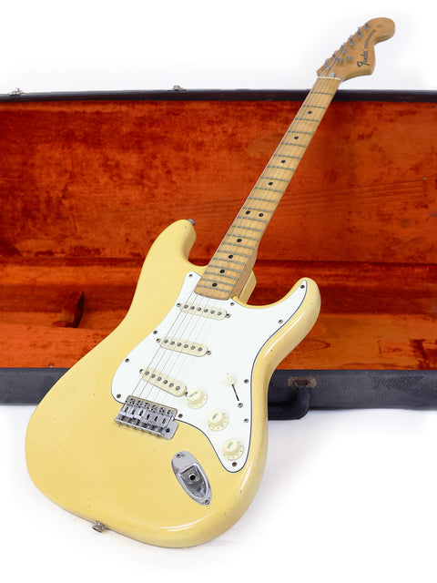 A vintage 1954 Fender Stratocaster electric guitar, yellow in color, displayed in an old case, emphasizing its historical significance.