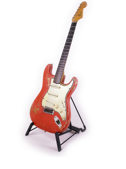 A vintage 1964 Fender L Series Stratocaster in Fiesta Red displayed on a stand against a white background.
