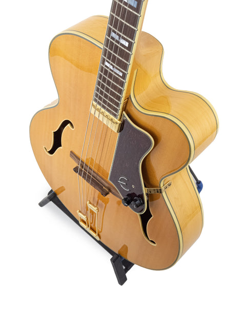 vintage 1965 Epiphone Coronet guitar displayed on a stand, set against a stark white backdrop.