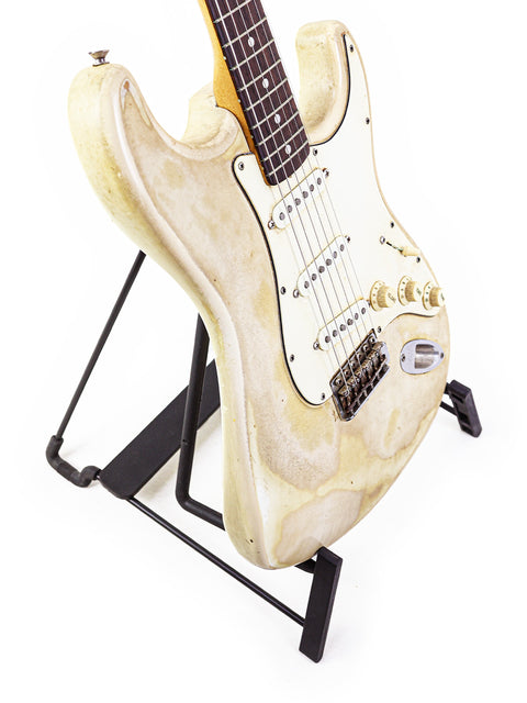  A vintage 1968 Fender Stratocaster in white, beautifully positioned on a stand with a modern black base for added elegance.