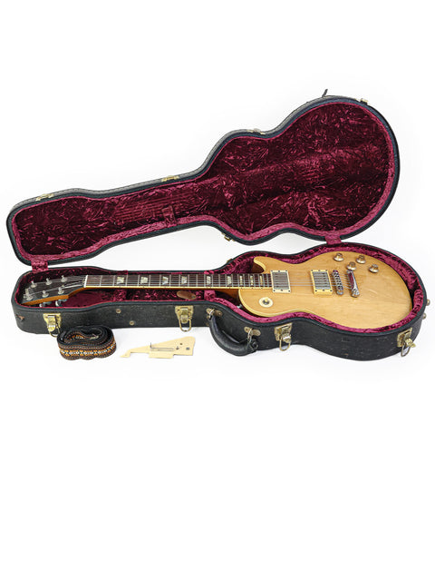 A vintage 1973 Gibson Les Paul Deluxe is nestled in a guitar case, representing iconic American craftsmanship.