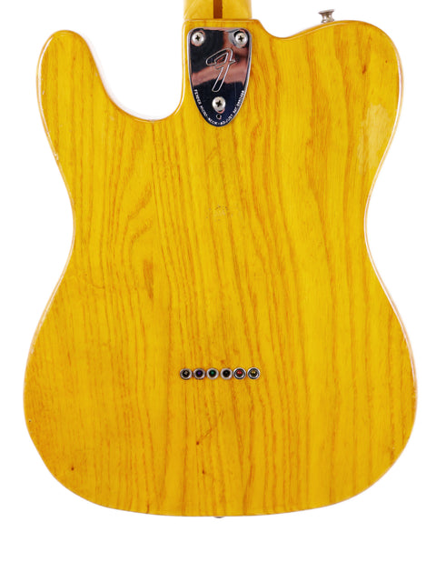 A vintage 1977 Fender Telecaster Custom, featuring a yellow finish, white body, and striking black pickguard.
