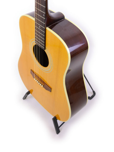 A vintage 1989 Guild D40 acoustic guitar resting on a stand, highlighting its compact size and beautiful wood finish.
