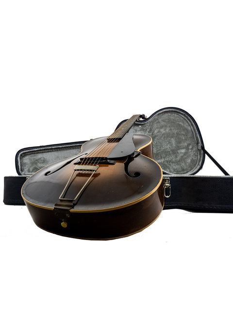A vintage Epiphone Masterbilt Zenith guitar from 1935 positioned in its case with a white background.