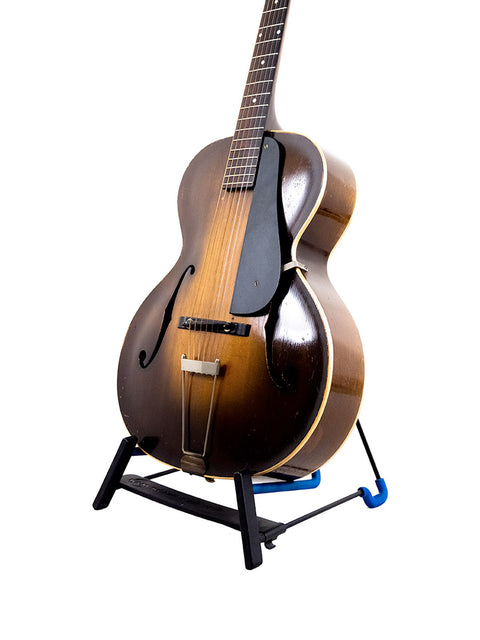 A vintage Epiphone Masterbilt Zenith guitar from 1935 resting on a stand with a stylish black base.