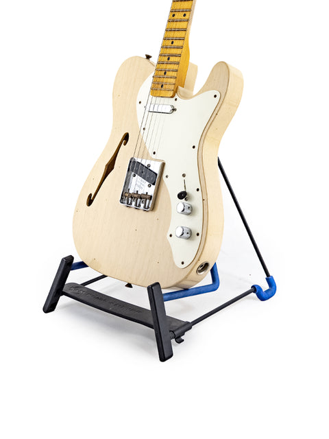 A vintage Fender Custom Shop '50s Thinline Relic Telecaster guitar resting on a blue stand, highlighting its unique craftsmanship.