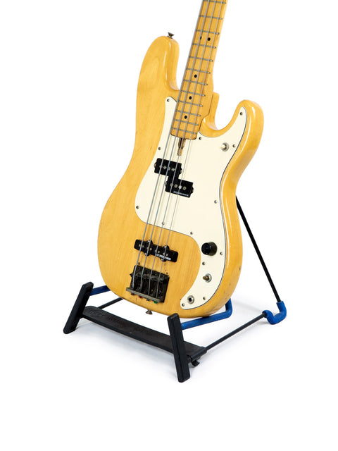 A vintage Greco PB 750 electric bass guitar displayed on a stand, featuring a white background that highlights its details.