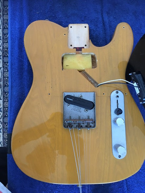 A vintage yellow Fender Squier JV Telecaster guitar with a pickguard and a pick, showcasing its 1984 design.

