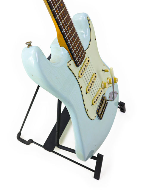  A white '59 Stratocaster electric guitar from Fender Custom Shop, resting on a stand, emphasizing its classic style.