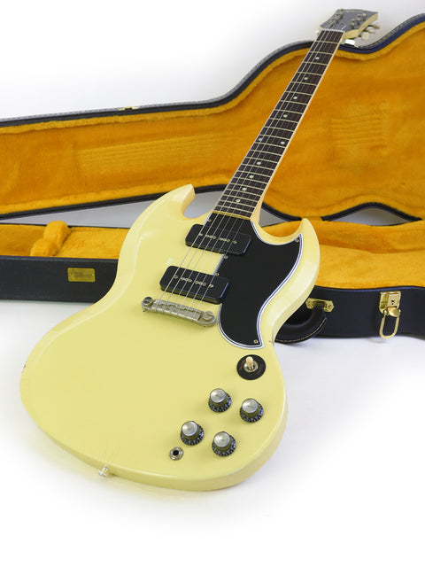 A white electric guitar, the Gibson Custom ‘63 SG Special, nestled in its protective case, highlighting its elegant features.