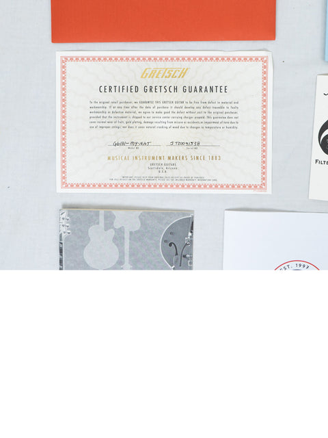 A white table showcases a certificate of authenticity for the Gretsch G6131 Malcolm Young Signature Jet from Japan, 2020.