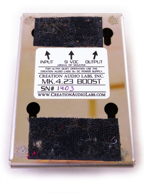 A worn-out guitar pedal labeled "MK.4.23 BOOST" with input/output specifications.