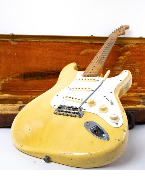 A yellow 1959 Fender Stratocaster guitar with a maple neck, resting in a wooden case, highlighting its vintage appeal.
