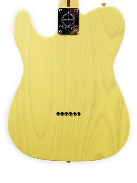 A yellow electric guitar body with six bridge pins and a black neck plate.