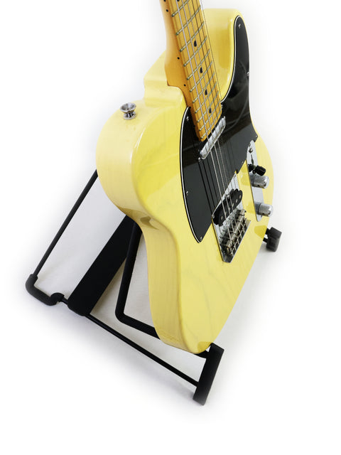 A yellow electric guitar resting on a black stand against a white background.