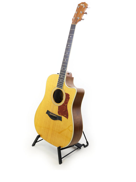 Acoustic guitar on a stand, model Taylor 410CE from 2011, set against a clean white background.