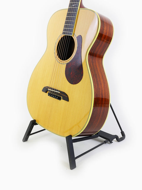 An Alvarez Yairi FYM95V guitar resting on a stand, featuring a striking white background that emphasizes its stunning details.
