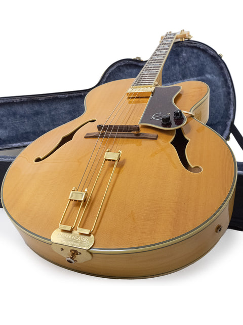 An Epiphone Coronet guitar from 1965 resting in its case on a white backdrop.
