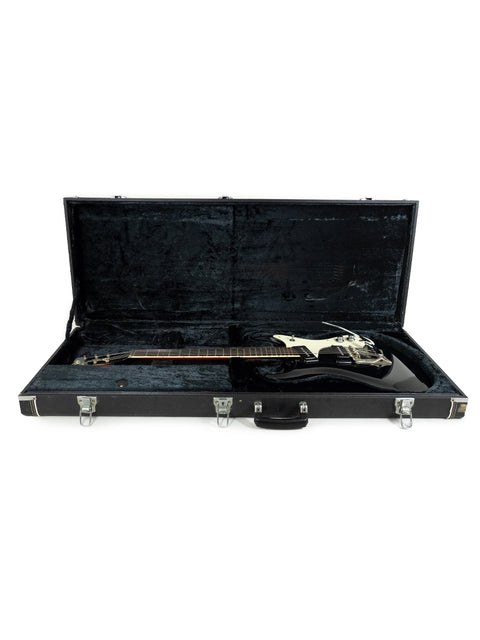 An open black guitar case displaying a black Mosrite Of California guitar, model from the 1990s, highlighting its elegant features.