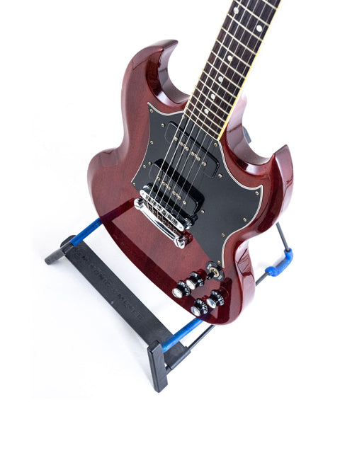 Beautifully crafted Gibson SG Classic guitar on a stand, complemented by a blue strap, perfect for aspiring musicians and collectors.