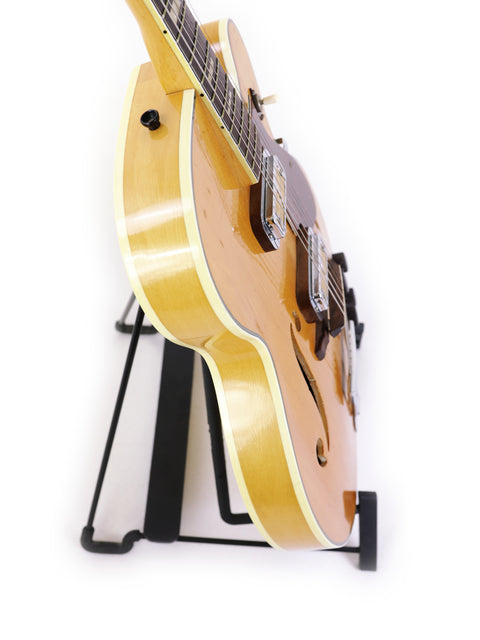 Beautifully crafted Harmony H71 Meteor guitar on a stand, ideal for music lovers, with a minimalist white background.
