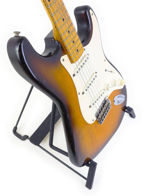 Black-bodied Vintage Fender Stratocaster guitar with a brown neck, representing the iconic 1954 USA design.