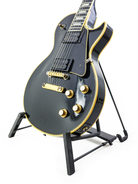 Black 1969 Gibson Les Paul Custom electric guitar resting on a stand, showcasing its vintage design.