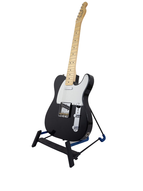 Black Fender Custom Shop guitar displayed on a stand with a blue base, marking the 30th Anniversary of the ’51 Nocaster NOS.

