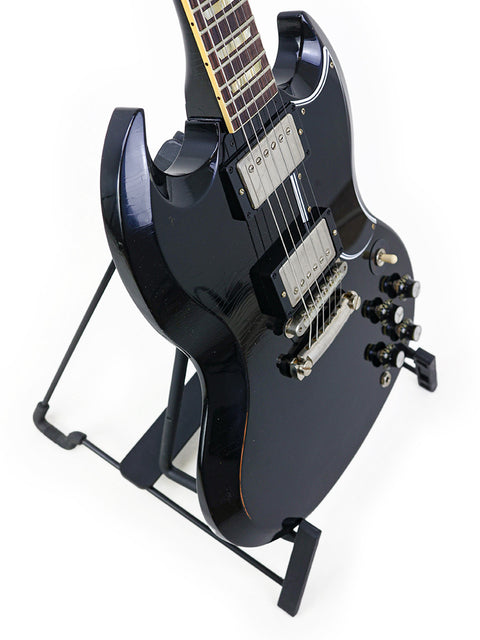 Black Gibson Custom Shop '64 SG electric guitar on a stand, highlighting its premium design and 2022 craftsmanship.