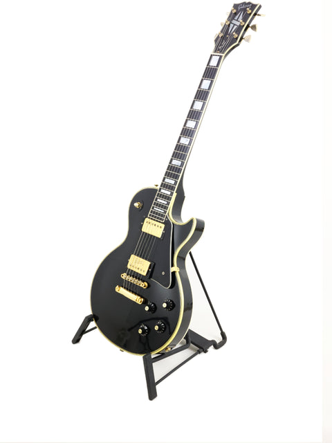 Black Gibson Les Paul Custom guitar from 1972 on a stand, set against a bright white background.