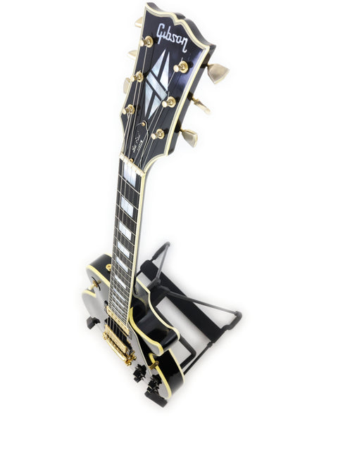 Black and gold 1972 Gibson Les Paul Custom guitar on a stand, highlighting its vintage design and craftsmanship.