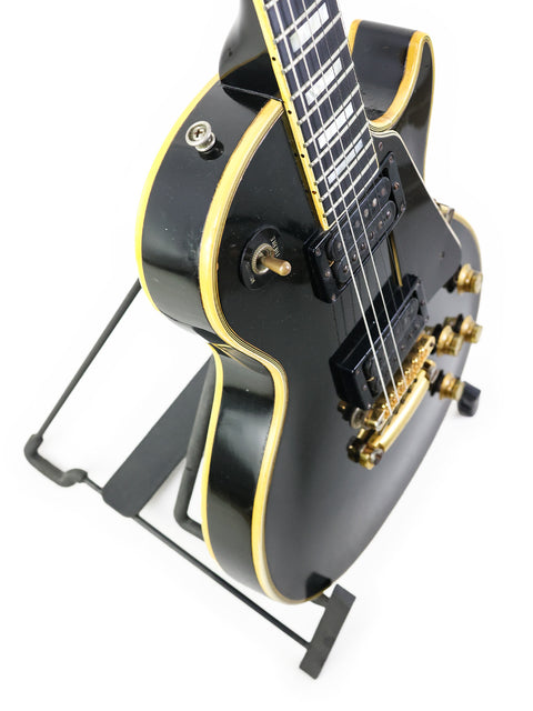 Black and gold Gibson Les Paul Custom guitar from 1969, proudly resting on a stand, a true vintage masterpiece.