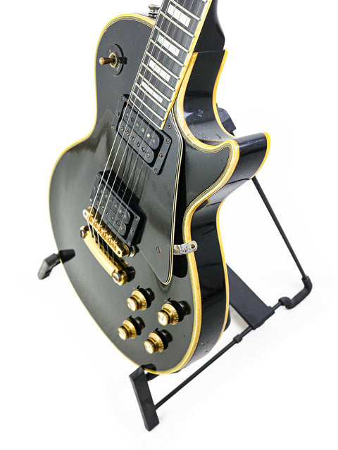 Black and gold Gibson Les Paul Custom guitar from 1969, proudly resting on a stand, embodying vintage rock elegance.