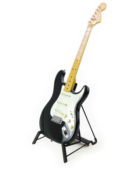 Black and white photo of a 1981 USA Fender Stratocaster guitar on a stand, capturing its timeless elegance.
