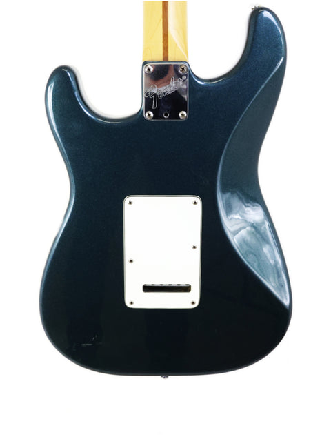Black electric guitar, Fender Strat Plus Deluxe model from 1989, adorned with a striking white pickguard.