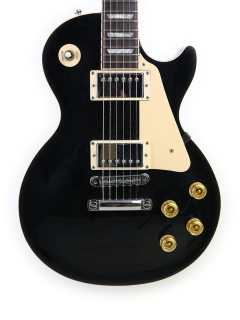 Black electric guitar, a 1995 Gibson Les Paul Standard, adorned with elegant gold hardware, showcasing its premium design.