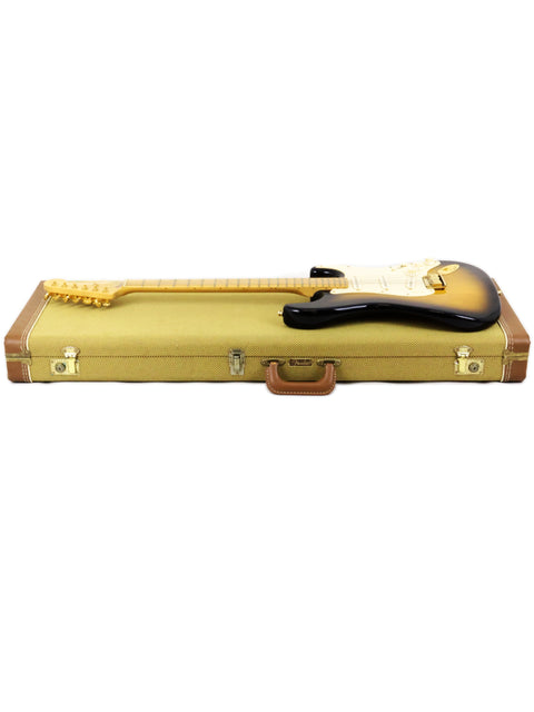 Black electric guitar on a beige case against a white background.