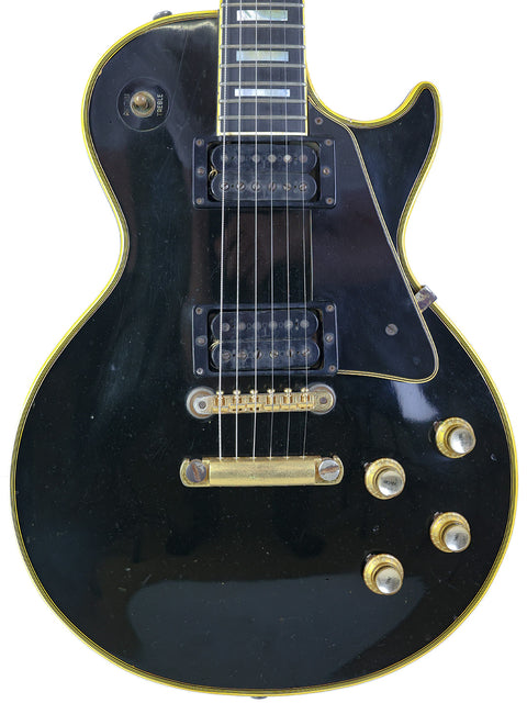 Black electric guitar with a gold pickguard, a vintage 1969 Gibson Les Paul Custom from the USA.