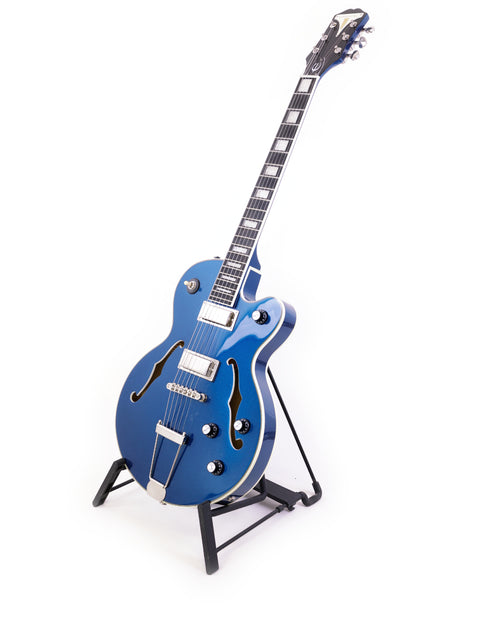 Blue Epiphone UpTown Kat ES guitar displayed on a stand with a bright white backdrop.