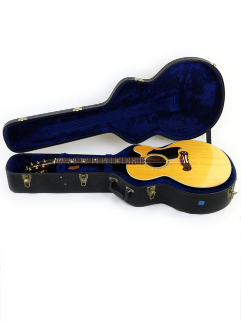 Blue guitar case housing a wooden-bodied Gibson J-180EC, crafted in the USA in 2001, highlighting its classic style.