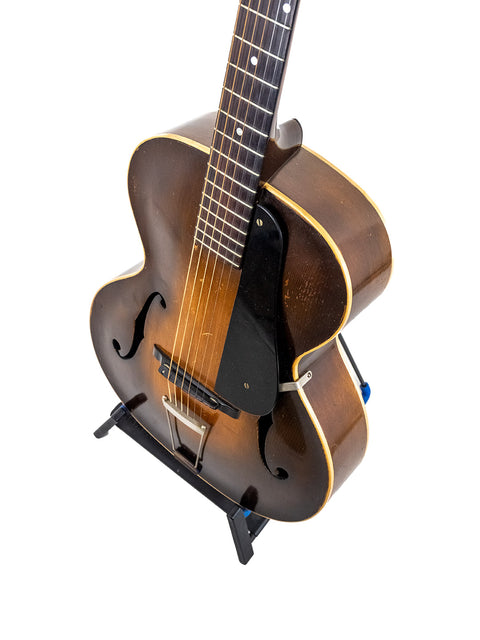 Classic 1935 Epiphone Masterbilt Zenith guitar on a stand, elegantly presented against a simple white backdrop.
